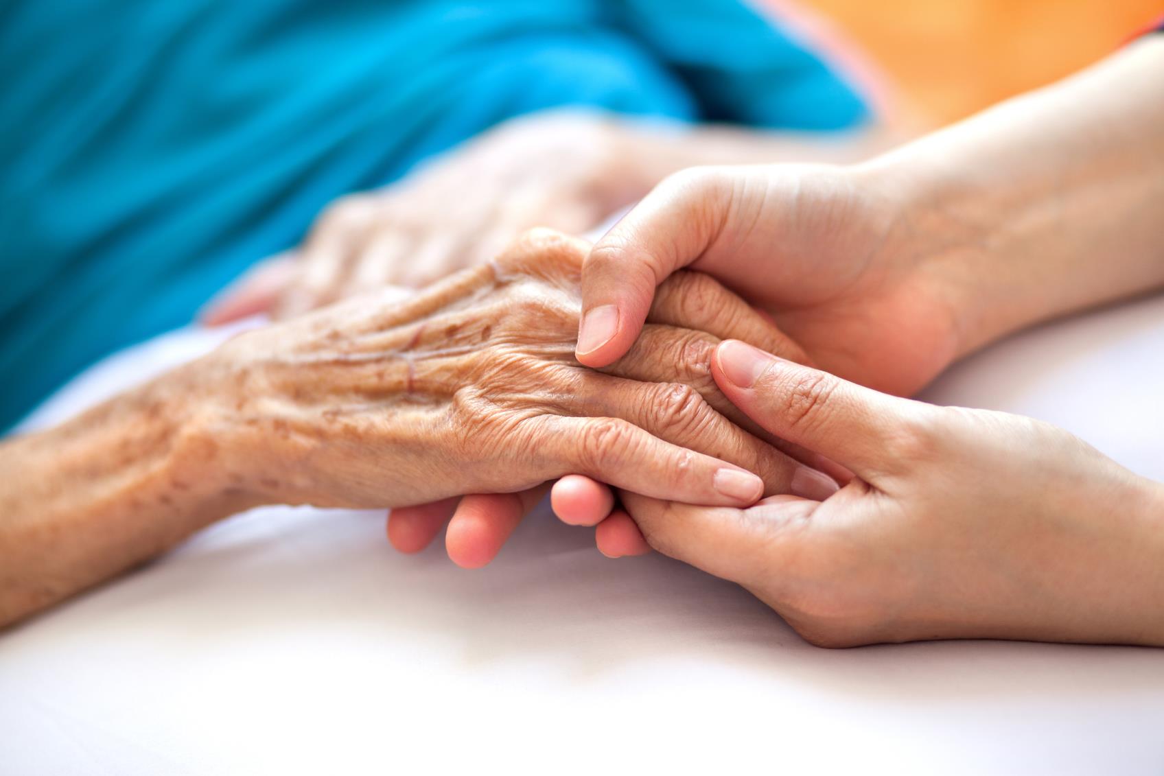 Close-up of younger person holding hand of older person