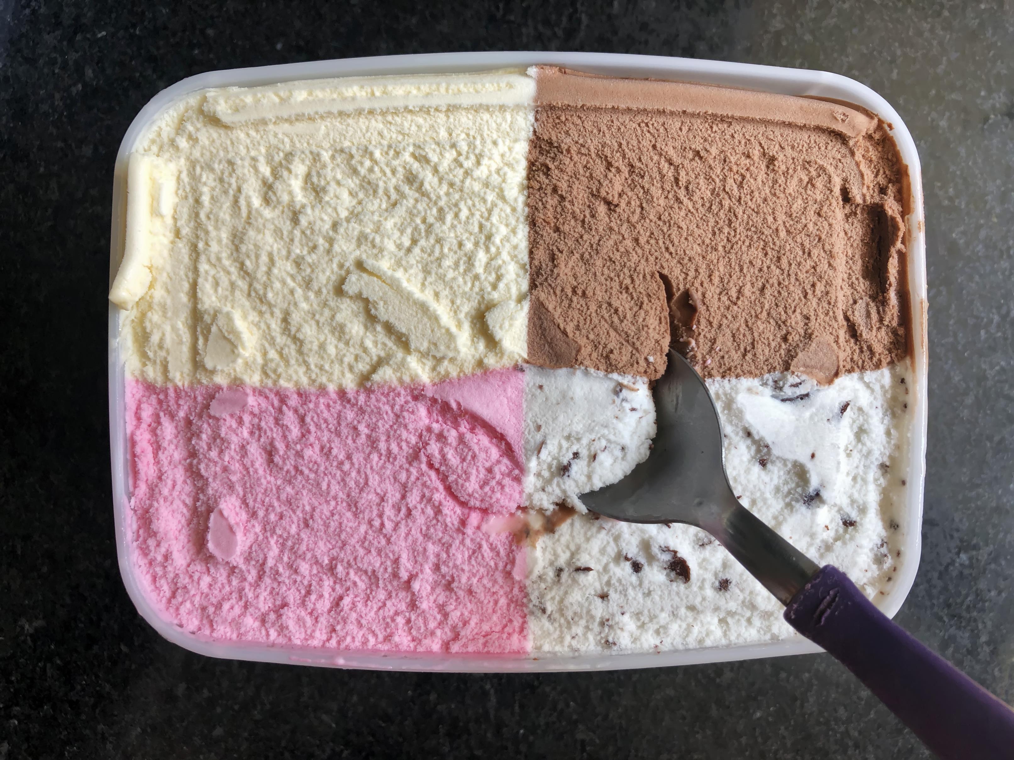 Ice cream co<em></em>ntain with four flavors – strawberry, vanilla, chocolate and coo<em></em>kies and cream – divided into four equal parts.