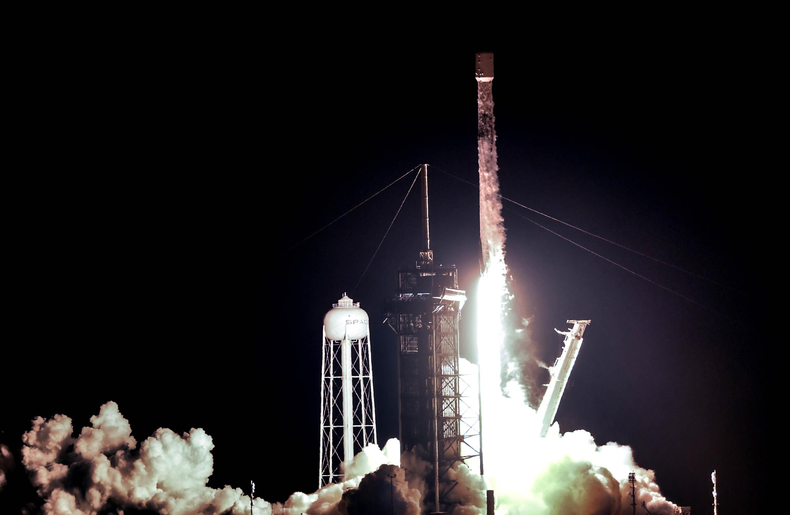 A rocket launched off a launch pad at night.